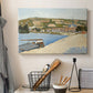 Canvas art print detailing a tranquil river composition with village, displayed in a softly lit workspace setting