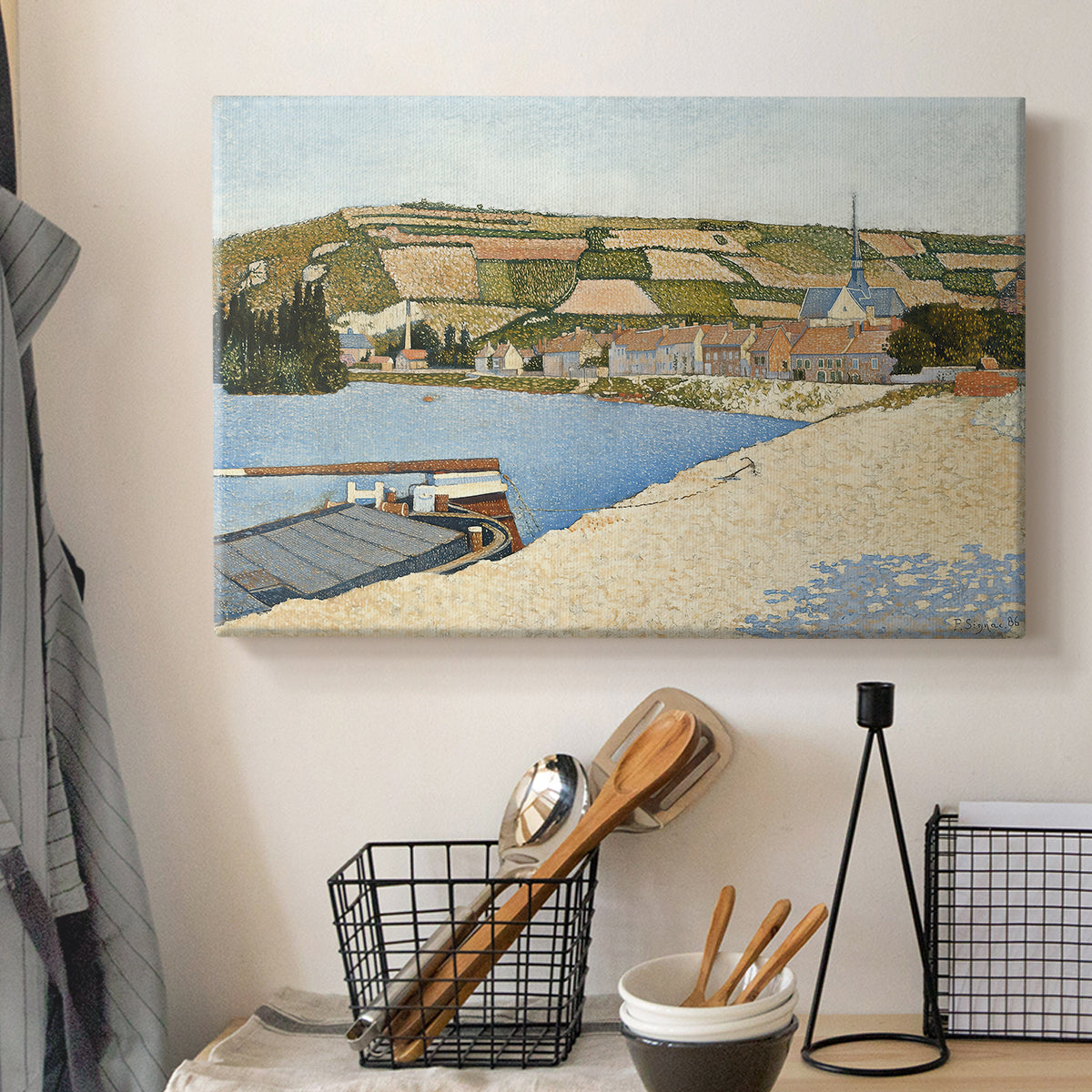 Canvas art print detailing a tranquil river composition with village, displayed in a softly lit workspace setting