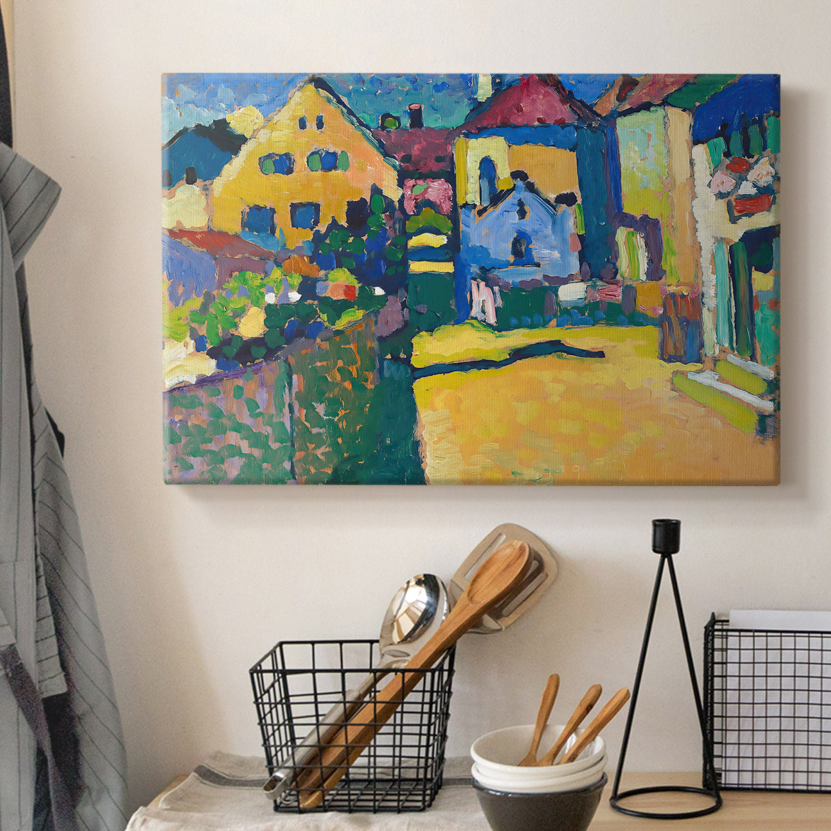 Canvas art print detailing a countryside street view with houses and greenery in vibrant tones, displayed in a softly lit workspace setting