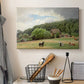 Canvas art print detailing a countryside setting with animals and farmhouse under soft sky, displayed in a softly lit workspace setting