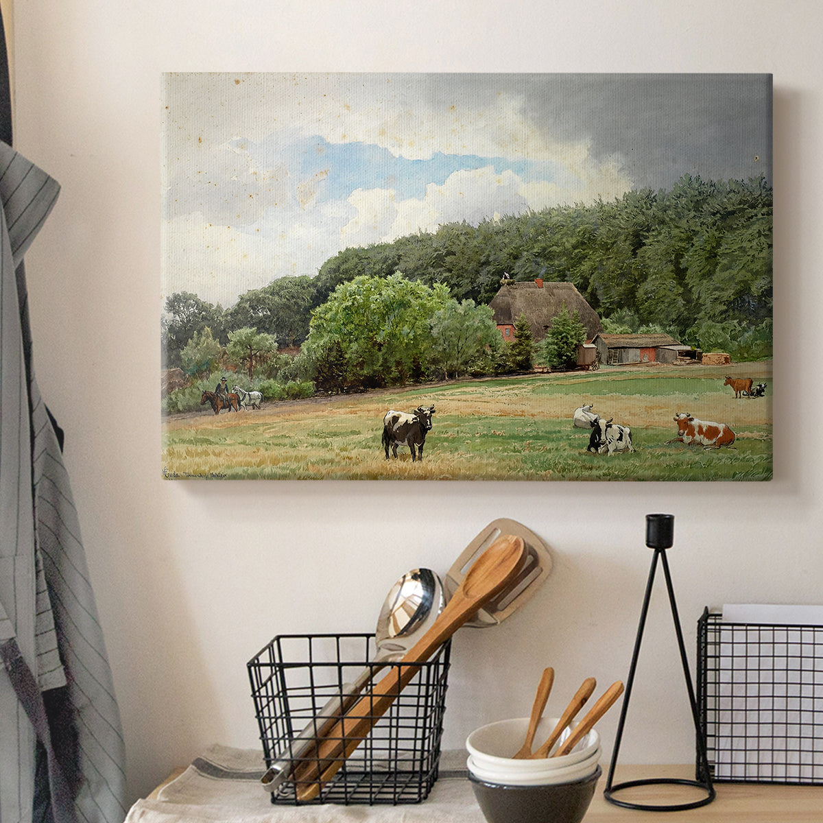 Canvas art print detailing a countryside setting with animals and farmhouse under soft sky, displayed in a softly lit workspace setting