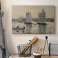 Canvas art print detailing a coastal view featuring two schooners under clear sky, displayed in a softly lit workspace setting
