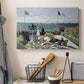 Canvas art print detailing a landscaped terrace with figures and flags near shoreline, displayed in a softly lit workspace setting