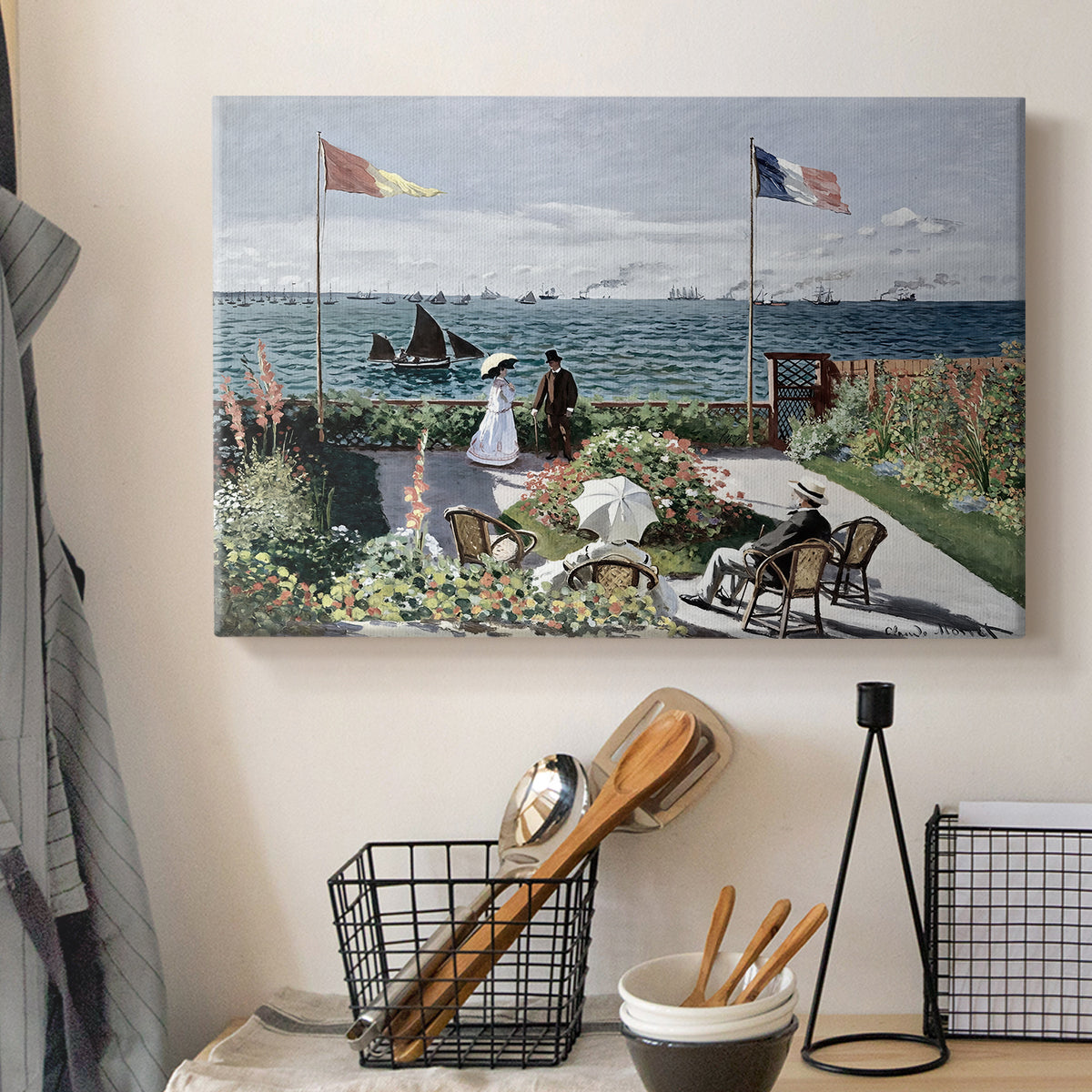 Canvas art print detailing a landscaped terrace with figures and flags near shoreline, displayed in a softly lit workspace setting