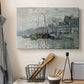 Canvas art print detailing a harbor view with masts, houses, and reflections in water, displayed in a softly lit workspace setting