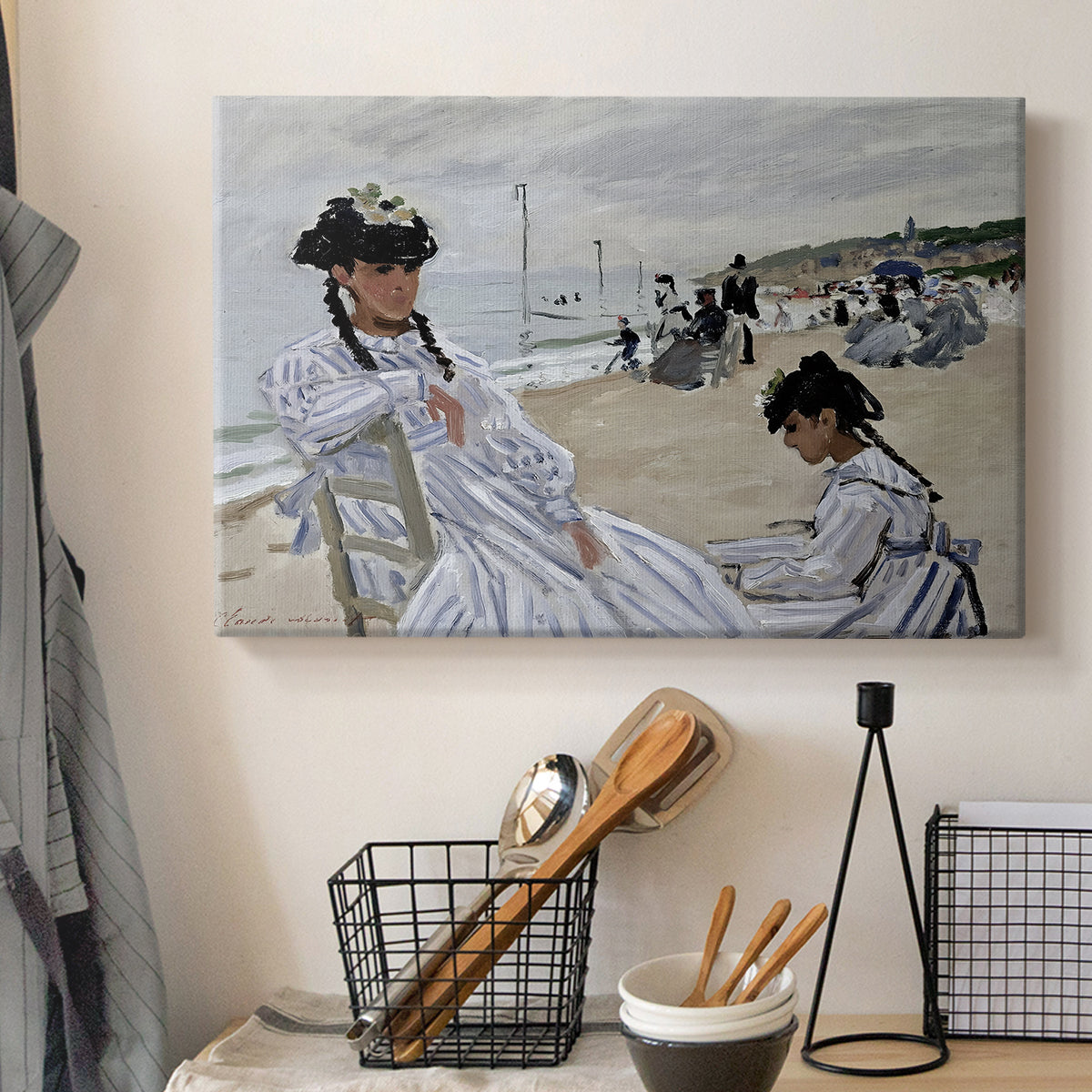 Canvas art print detailing a coastal leisure scene with figures looking out to sea, displayed in a softly lit workspace setting