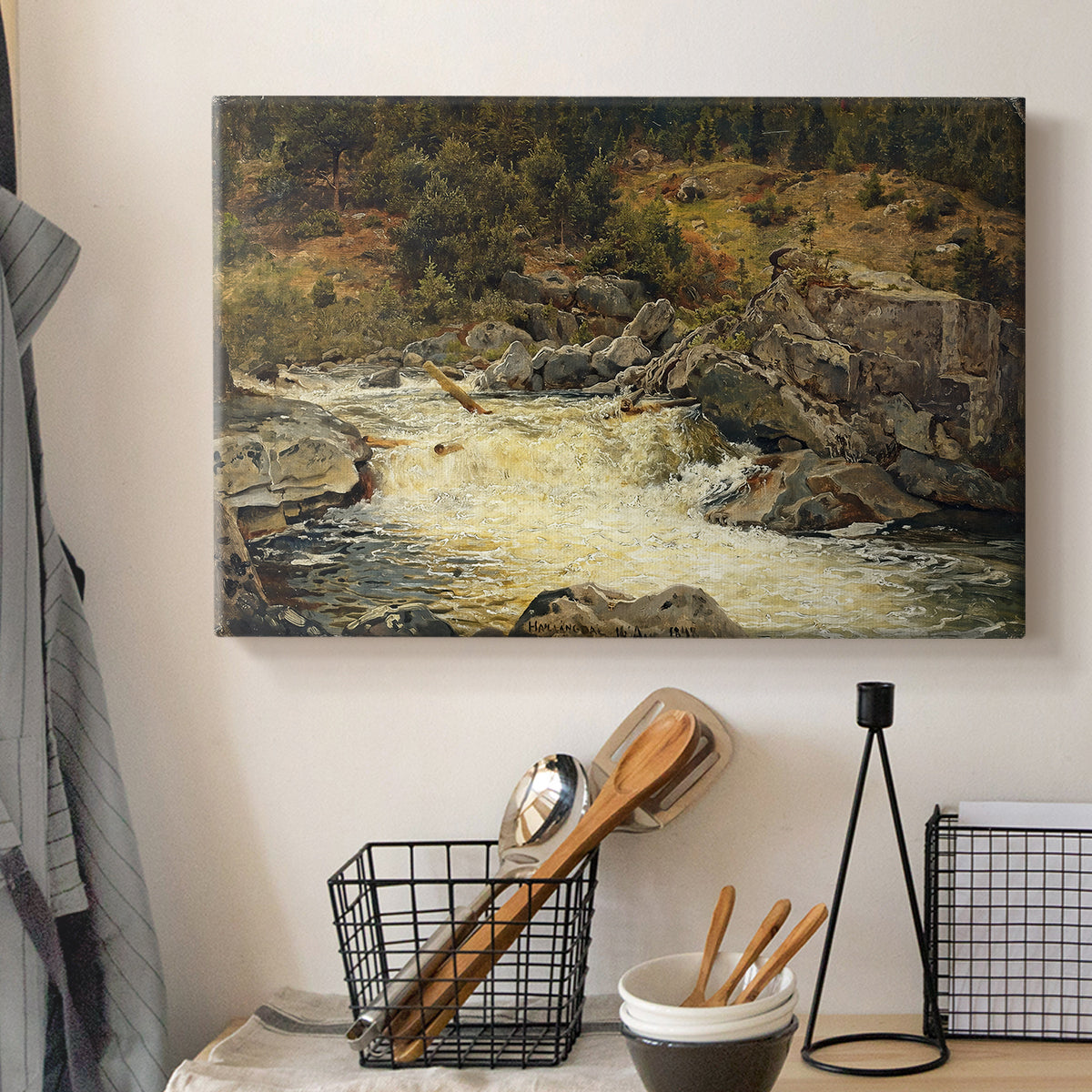 Canvas art print detailing a forested setting with stream descending over rocks, displayed in a softly lit workspace setting