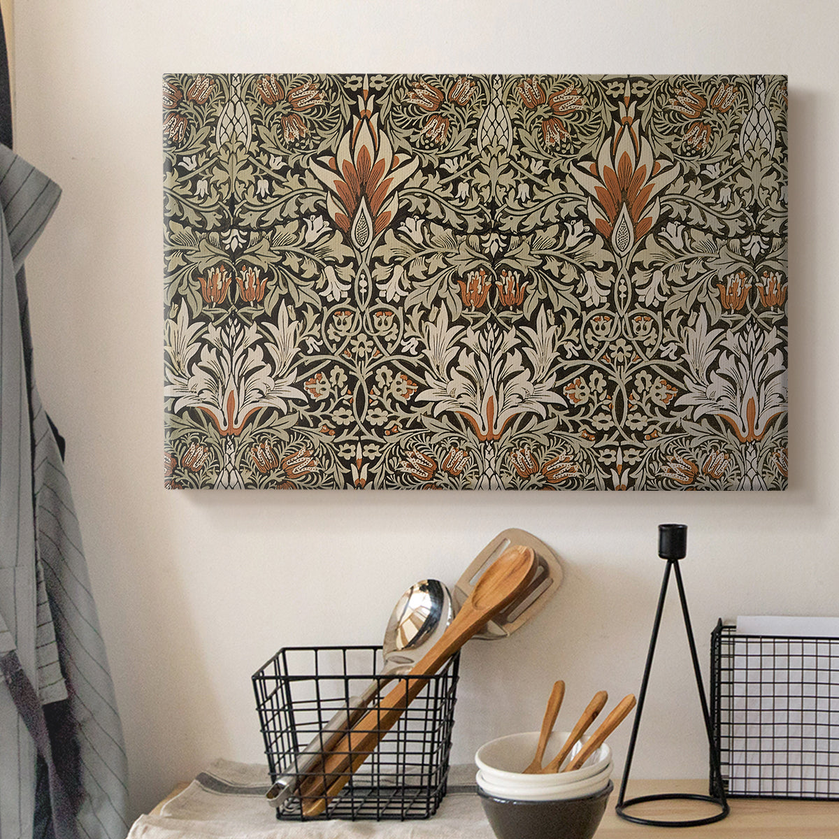 Canvas art print detailing a botanical motif with repeating curved stems on dark ground, displayed in a softly lit workspace setting
