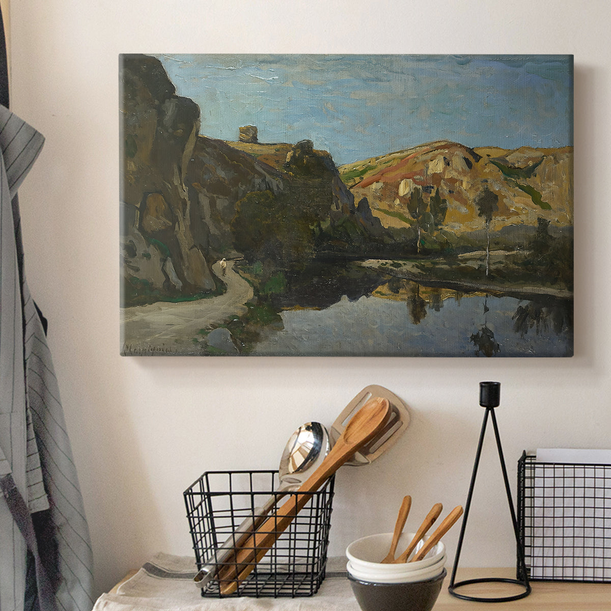 Canvas art print detailing a pastoral setting with water cutting through rugged terrain, displayed in a softly lit workspace setting