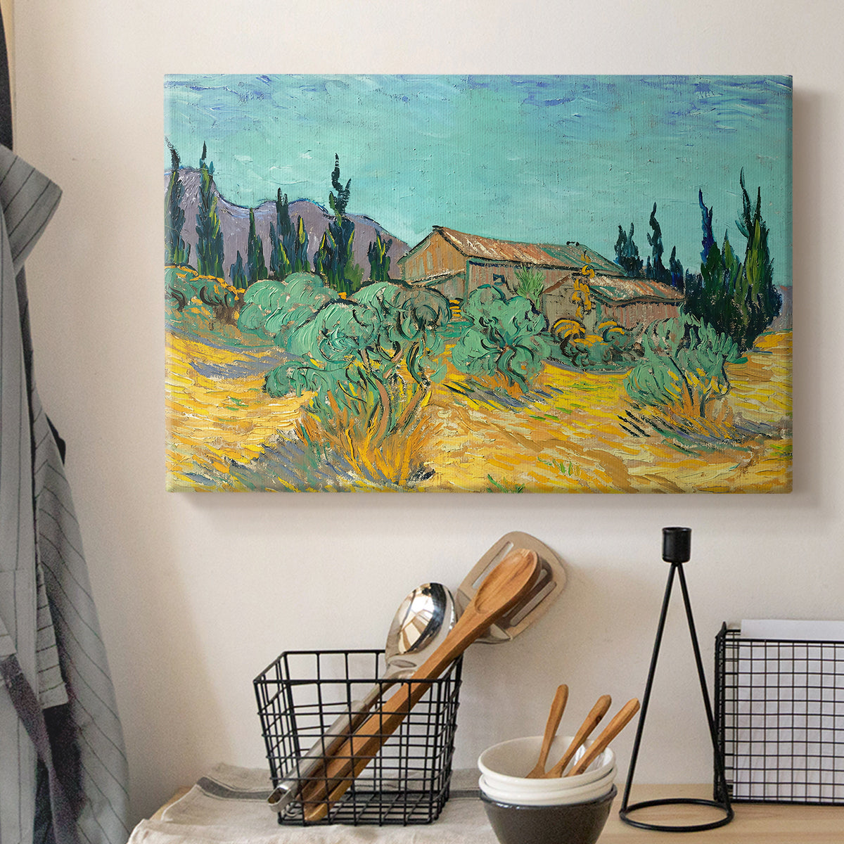 Canvas art print detailing a stylized rural setting with trees and structures, displayed in a softly lit workspace setting
