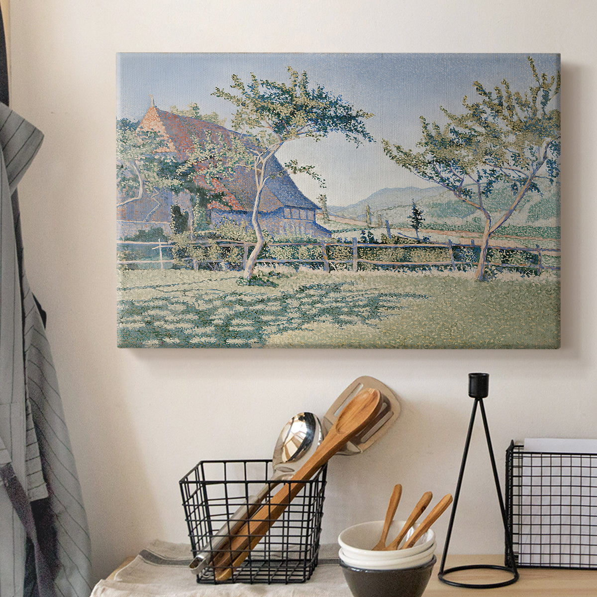 Canvas art print detailing a landscape with village and meadow, displayed in a softly lit workspace setting