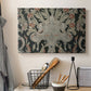 Canvas art print detailing a decorative fabric pattern with mixed botanical and animal forms, displayed in a softly lit workspace setting