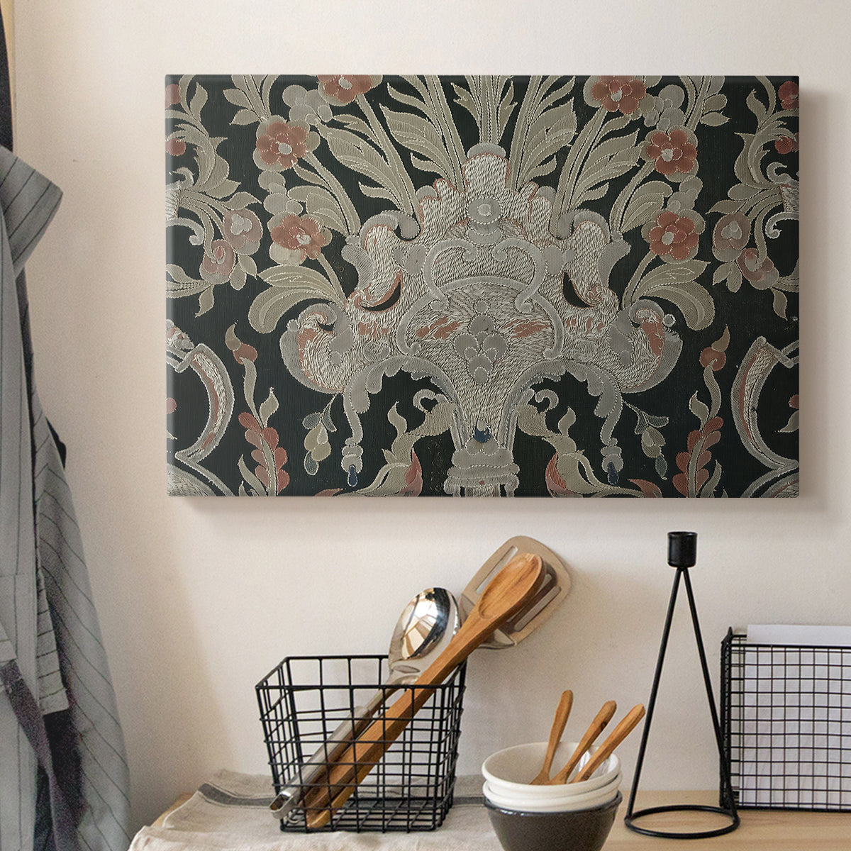 Canvas art print detailing a decorative fabric pattern with mixed botanical and animal forms, displayed in a softly lit workspace setting