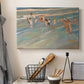 Canvas art print detailing a coastal scene with children and reflective shoreline, displayed in a softly lit workspace setting