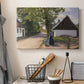 Canvas art print detailing a village setting with people and traditional architecture, displayed in a softly lit workspace setting