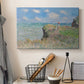 Canvas art print detailing an elevated shoreline path with figures and bright sky, displayed in a softly lit workspace setting