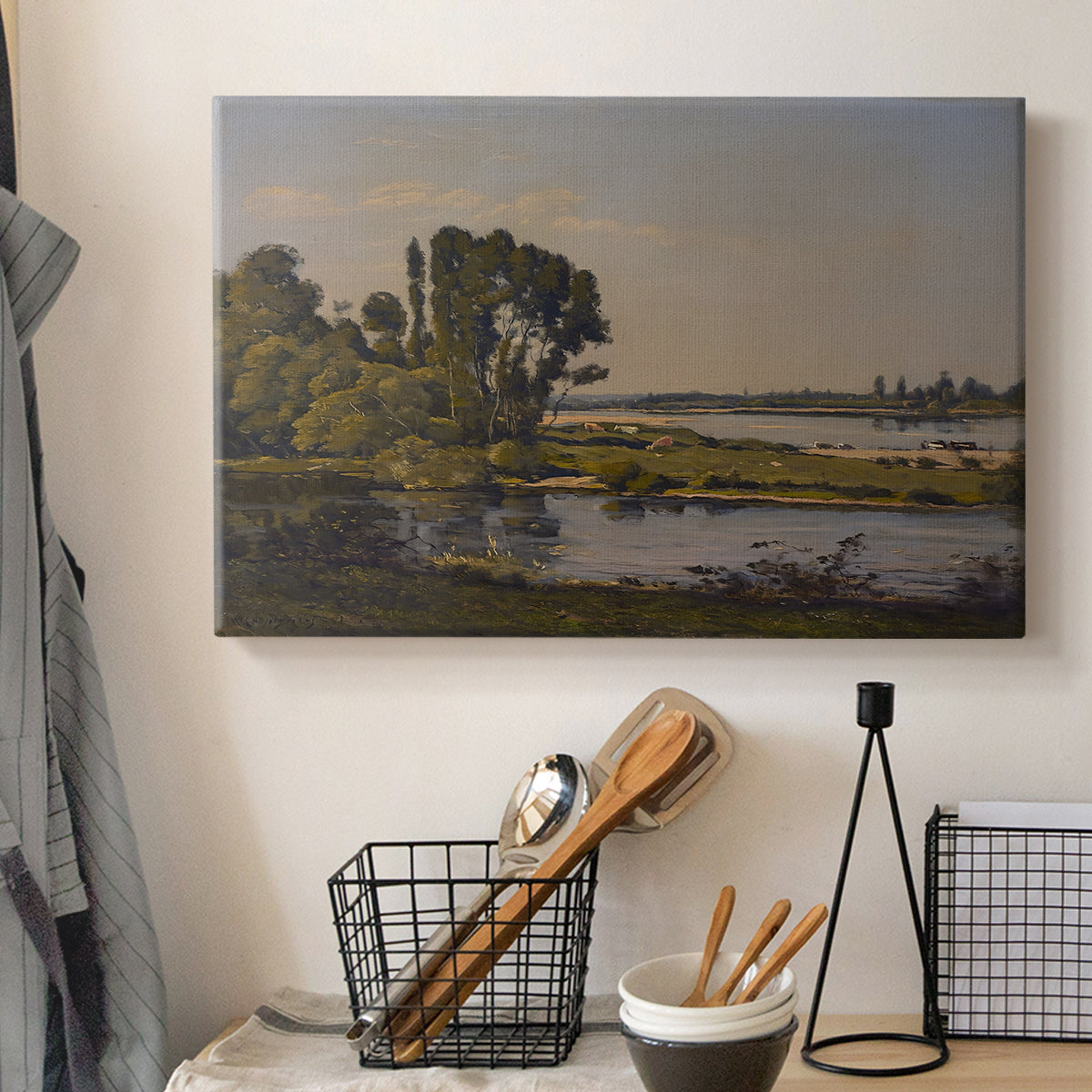 Canvas art print detailing a countryside scene with flowing water and greenery, displayed in a softly lit workspace setting