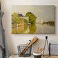 Canvas art print detailing a peaceful village scene with houses bordering water, displayed in a softly lit workspace setting