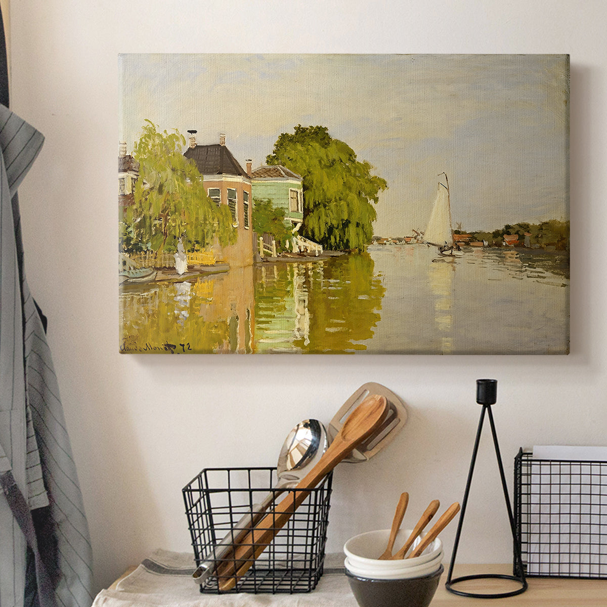 Canvas art print detailing a peaceful village scene with houses bordering water, displayed in a softly lit workspace setting
