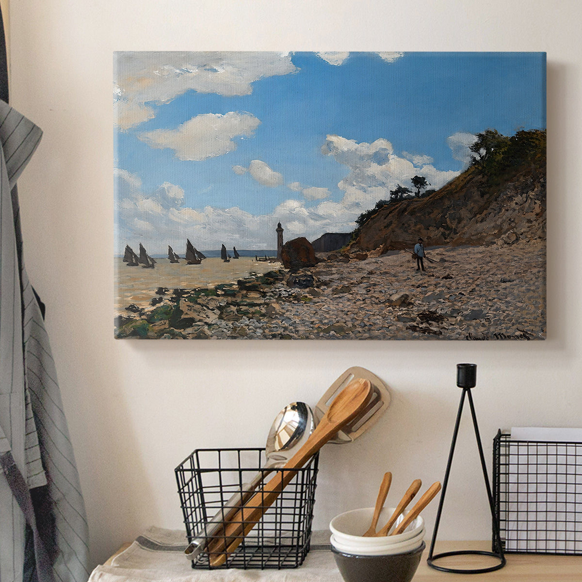 Canvas art print detailing a coastal landscape with boats and people along shore, displayed in a softly lit workspace setting