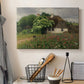 Canvas art print detailing a peaceful farmhouse view with natural vegetation, displayed in a softly lit workspace setting