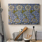 Canvas art print detailing a decorative composition with layered natural motifs and symmetry, displayed in a softly lit workspace setting