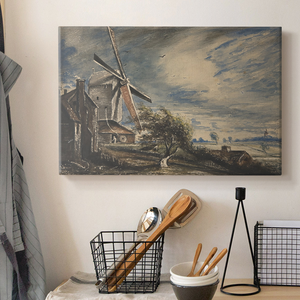 Canvas art print detailing a countryside view with mill and water, displayed in a softly lit workspace setting