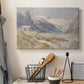Canvas art print detailing a natural landscape with human presence among mountains, displayed in a softly lit workspace setting