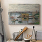 Canvas art print detailing a subdued urban landscape with structure spanning river, displayed in a softly lit workspace setting