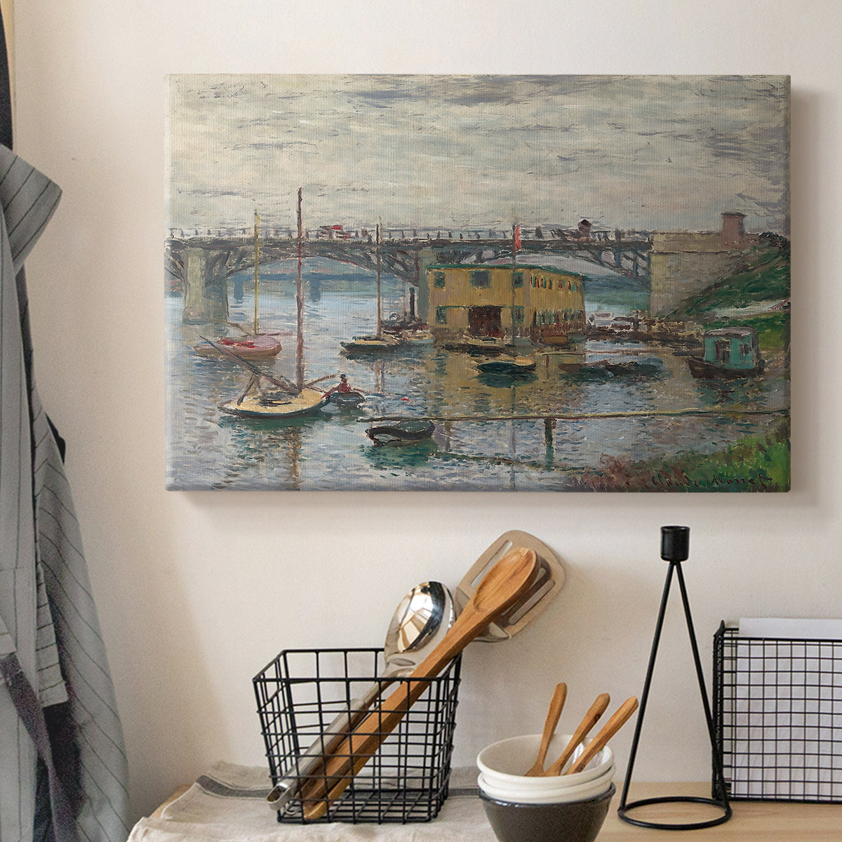 Canvas art print detailing a subdued urban landscape with structure spanning river, displayed in a softly lit workspace setting