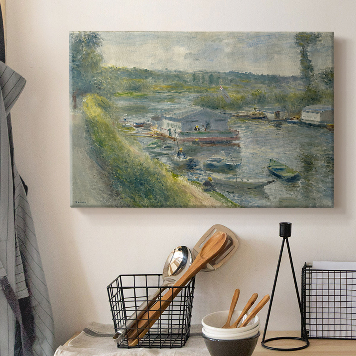 Canvas art print detailing an everyday life scene with boat and figures along river edge, displayed in a softly lit workspace setting