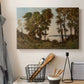 Canvas art print detailing a countryside setting with river and tree-lined banks, displayed in a softly lit workspace setting