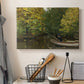 Canvas art print detailing a tranquil nature setting with lone figure by water, displayed in a softly lit workspace setting