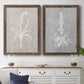 Set of two walnut barnwood framed canvas prints depicting a coordinated art pair of white botanical silhouettes on softly weathered neutral backgrounds rendered as rustic minimalist botanical prints above a dining room sideboard.