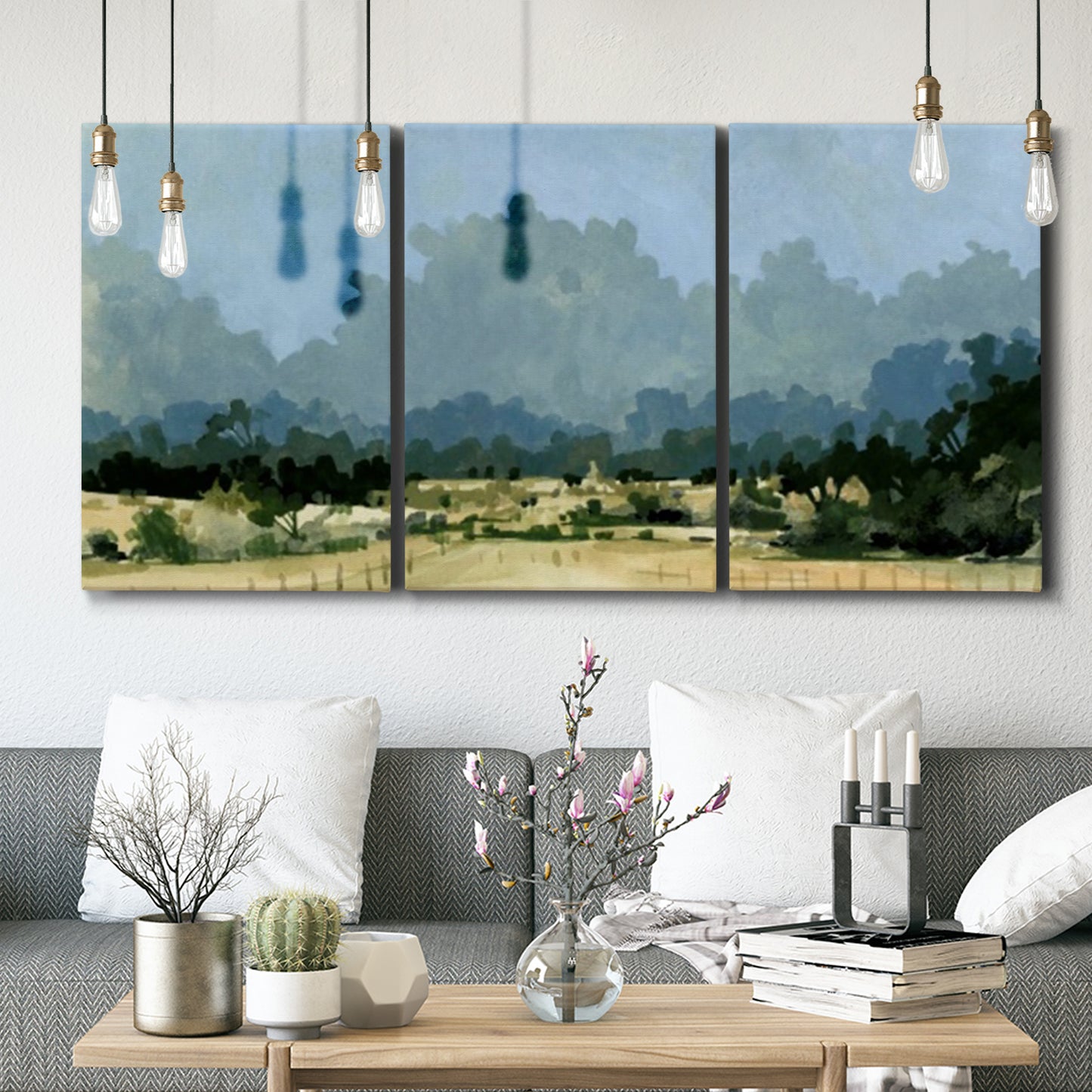 Three-panel canvas wall art featuring rural farmland landscape in watercolor, displayed in a modern living room above seating.