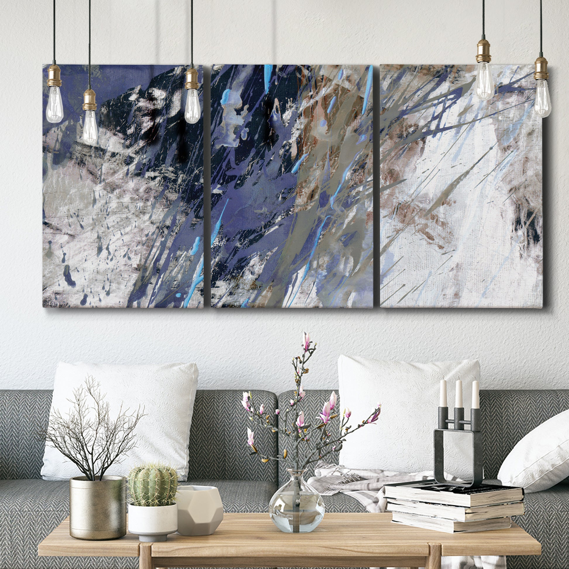 Three-panel canvas wall art featuring textured blue abstract composition, displayed in a modern living room above seating.
