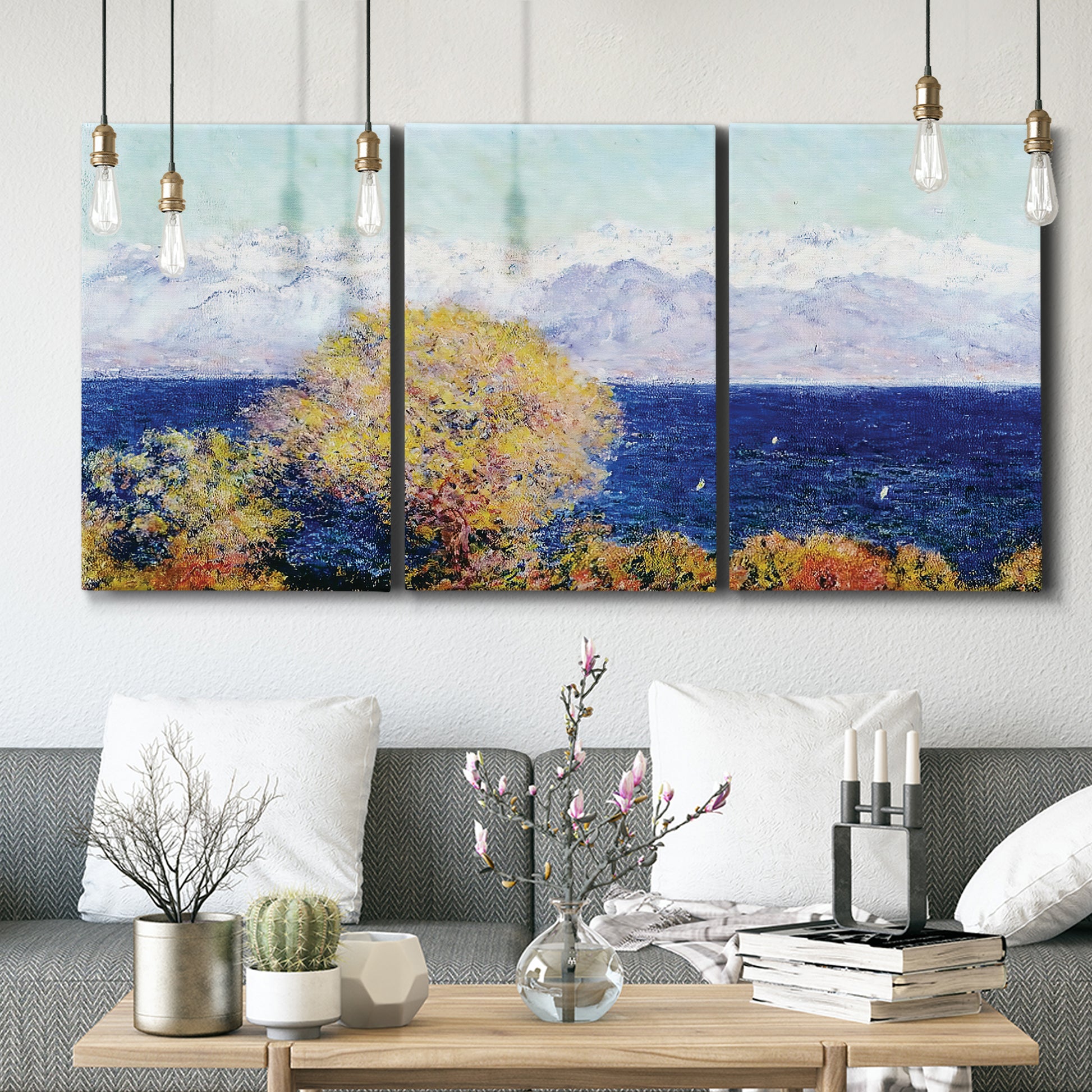 Three-panel canvas wall art featuring mediterranean coastline with headland, displayed in a modern living room above seating.