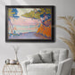 Pointillist coastal seascape by Paul Signac in an ornate black frame with gilded inner detail displayed in a bright interior setting.