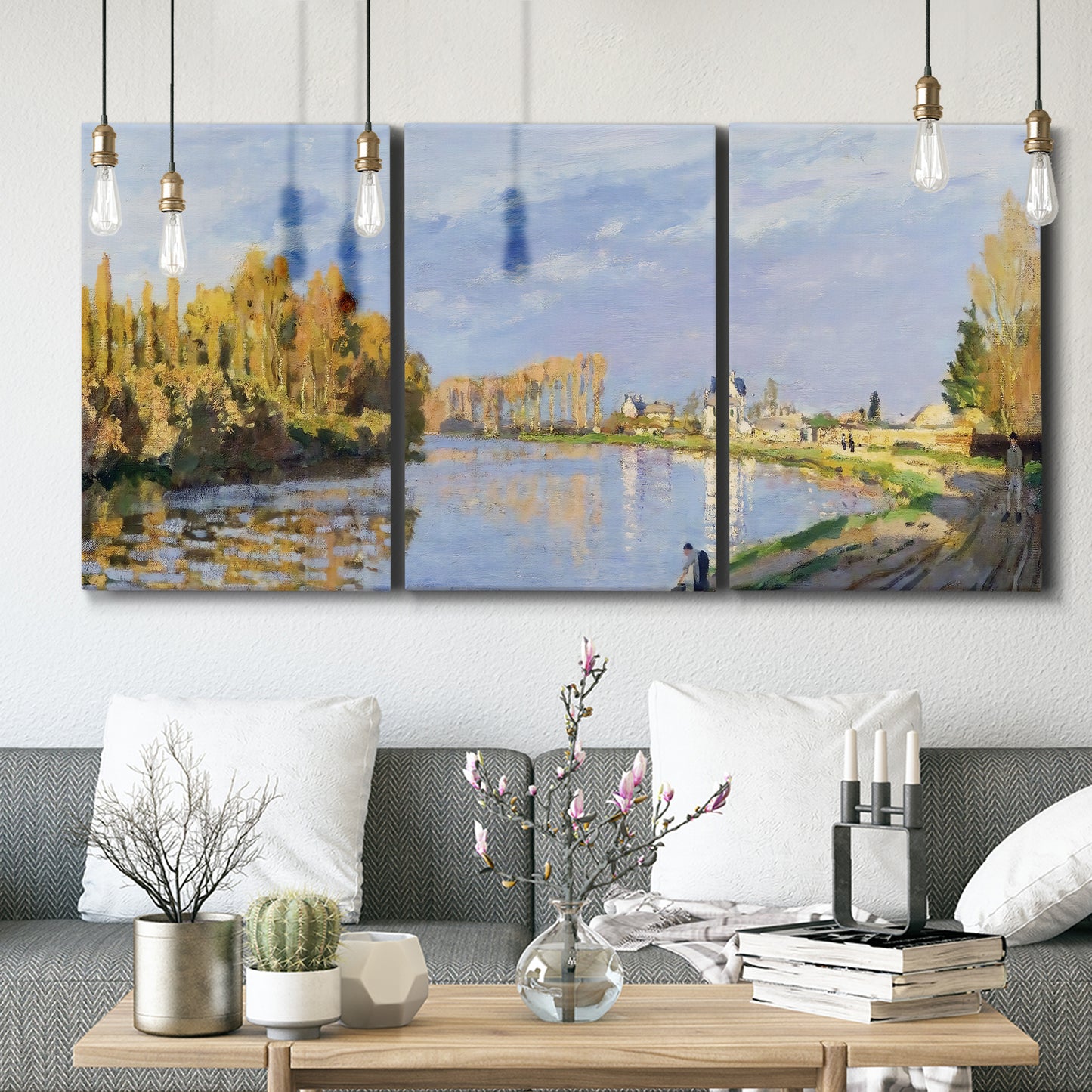 Three-panel canvas wall art featuring river flowing past village, displayed in a modern living room above seating.