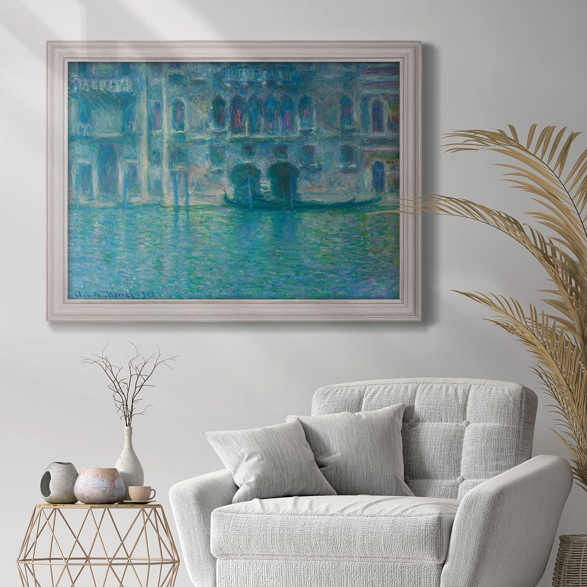 Impressionist Venetian palace waterfront scene by Claude Monet in an ornate weathered white frame displayed in a bright interior setting.