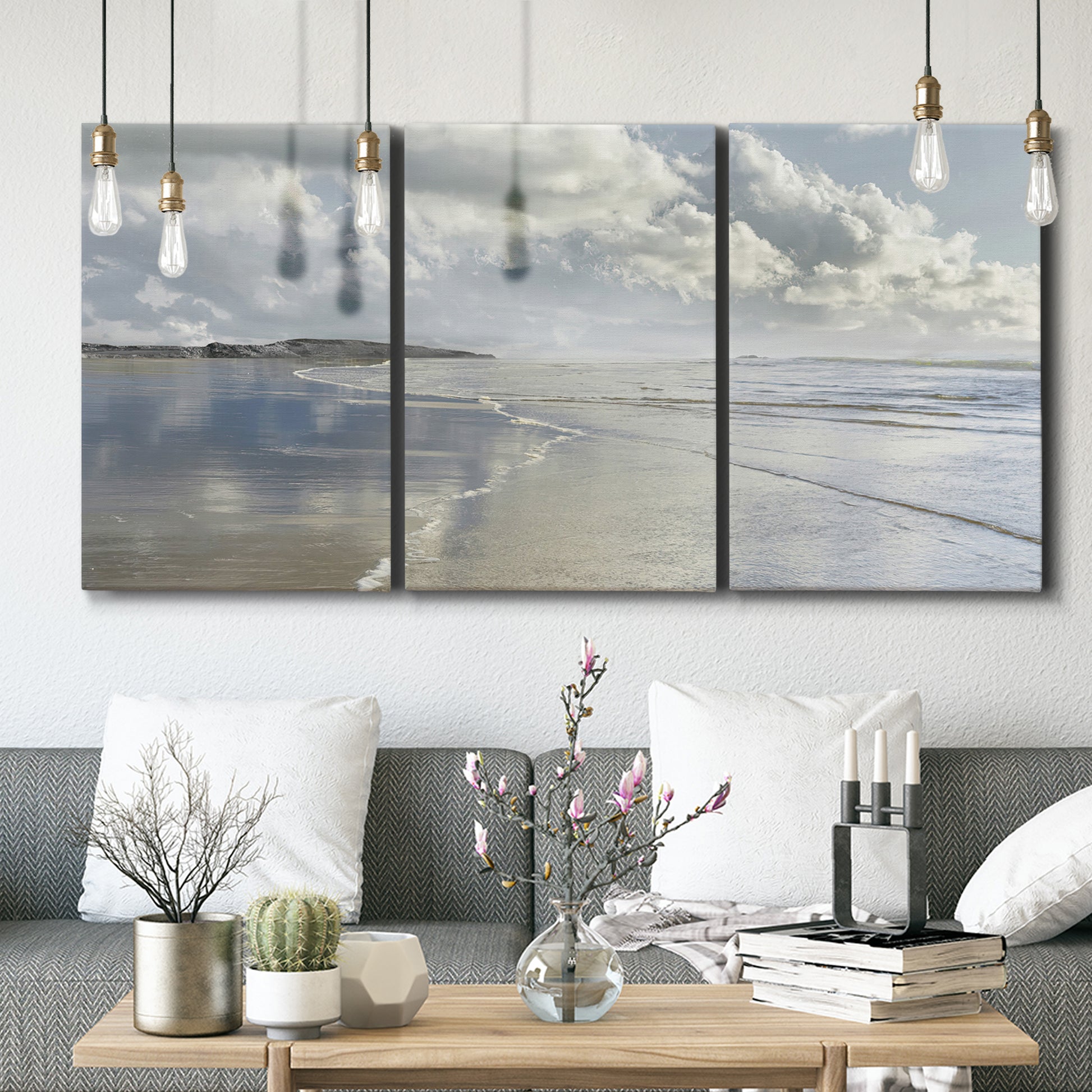 Three-panel canvas wall art featuring endless beach meeting ocean horizon, displayed in a modern living room above seating.