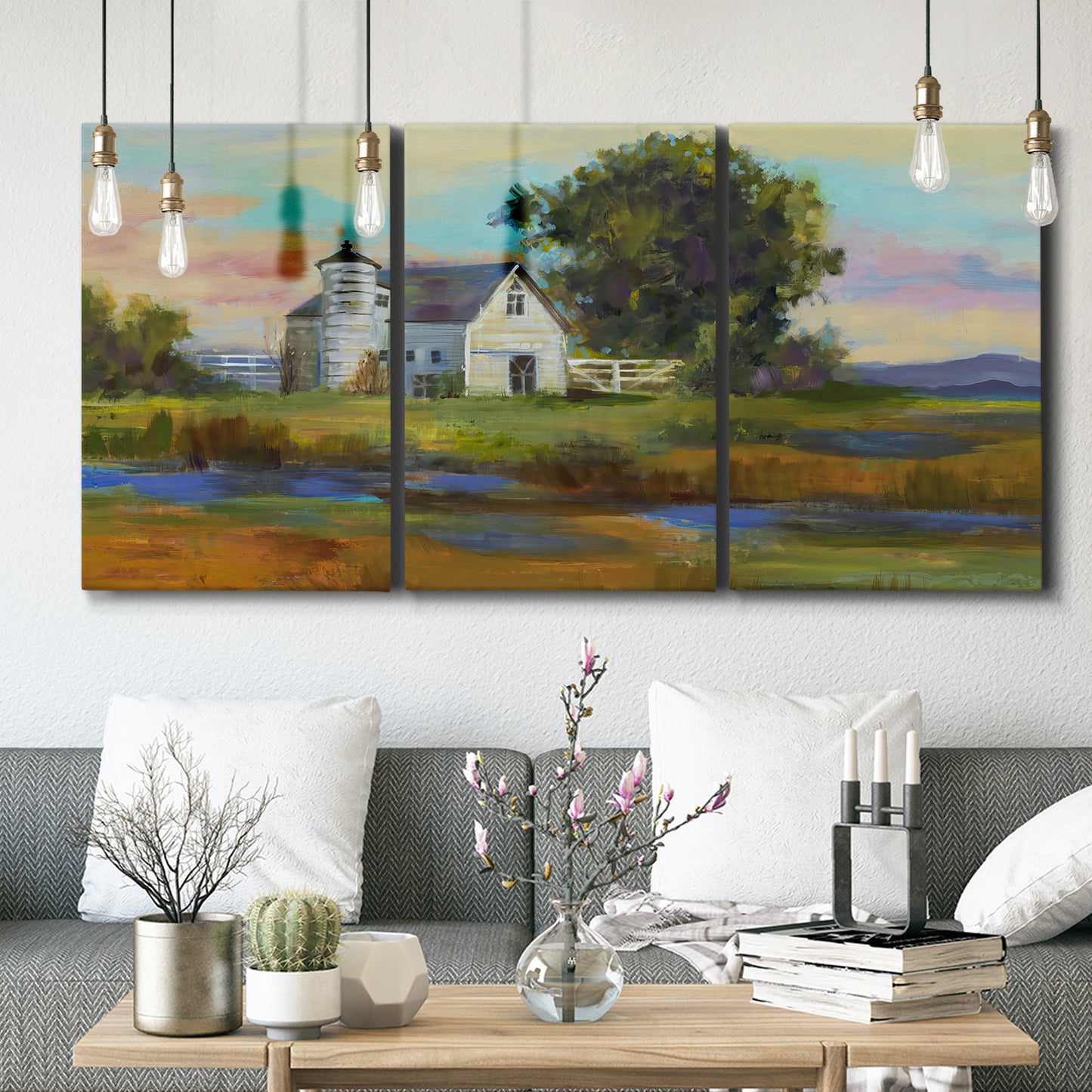 Three-panel canvas wall art featuring rural barn landscape with fields, displayed in a modern living room above seating.