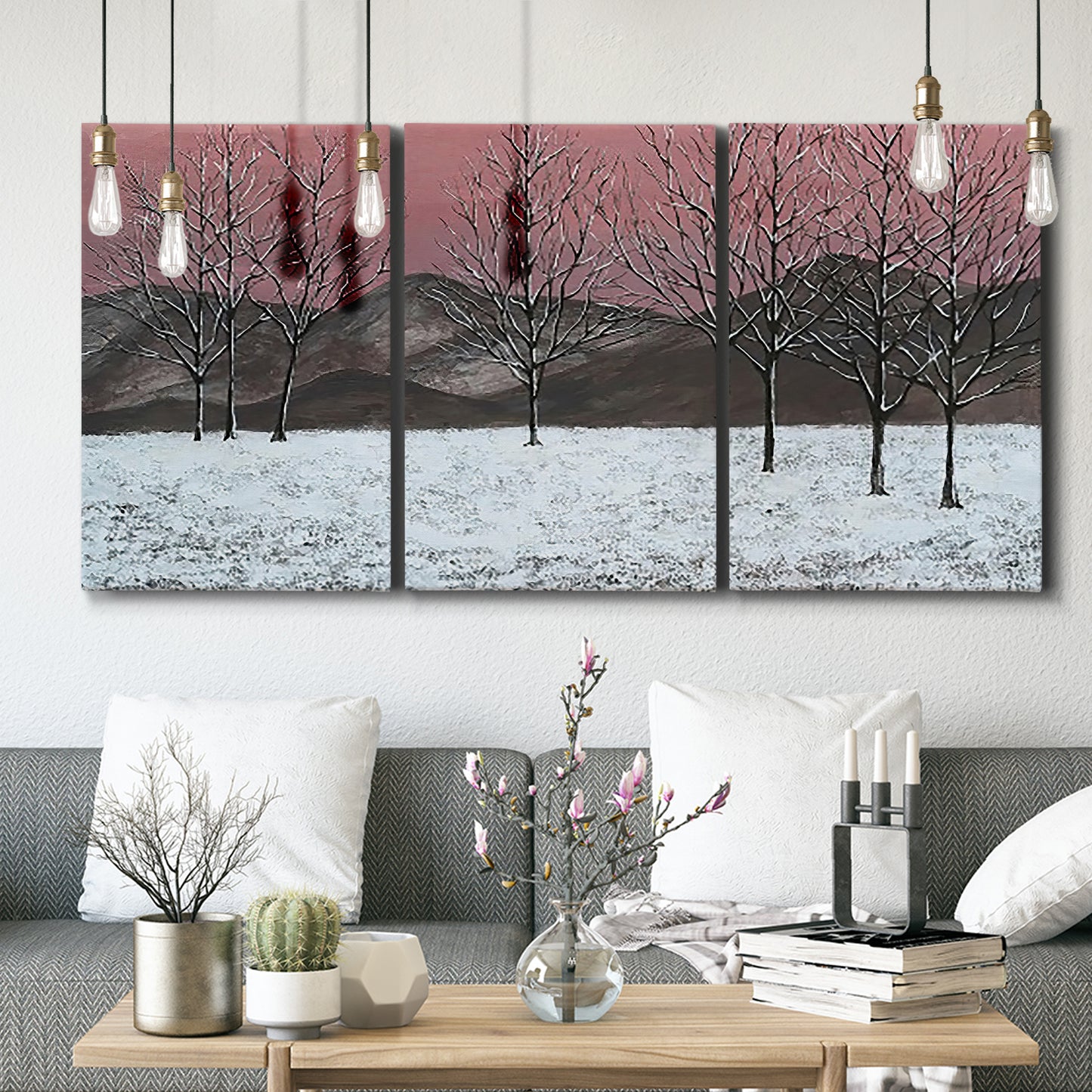 Three-panel canvas wall art featuring winter sunset snowfall landscape, displayed in a modern living room above seating.