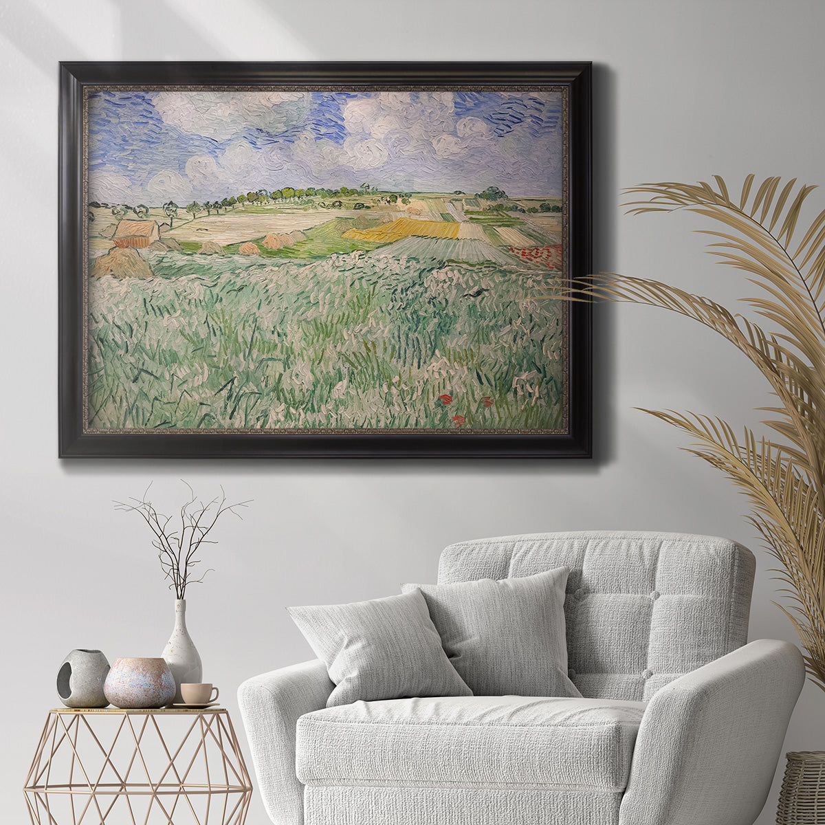 Impressionist countryside landscape near Auvers by Vincent van Gogh in an ornate black frame with gilded inner detail displayed in a bright interior setting.