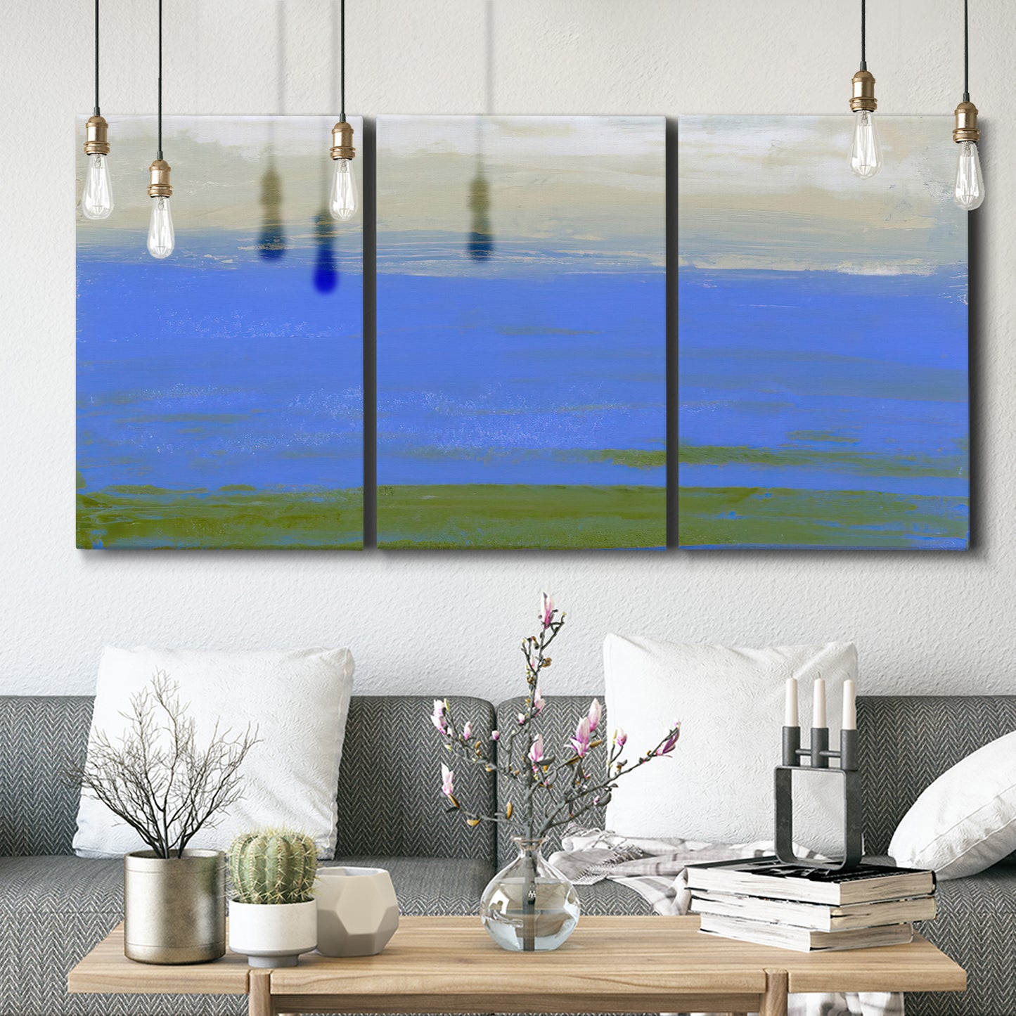 Three-panel canvas wall art featuring abstract coastal inlet landscape, displayed in a modern living room above seating.