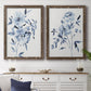 Set of two walnut barnwood framed canvas prints depicting a coordinated art pair of loose blue flowers and leafy branches rendered as expressive watercolor botanical paintings above a dining room sideboard.