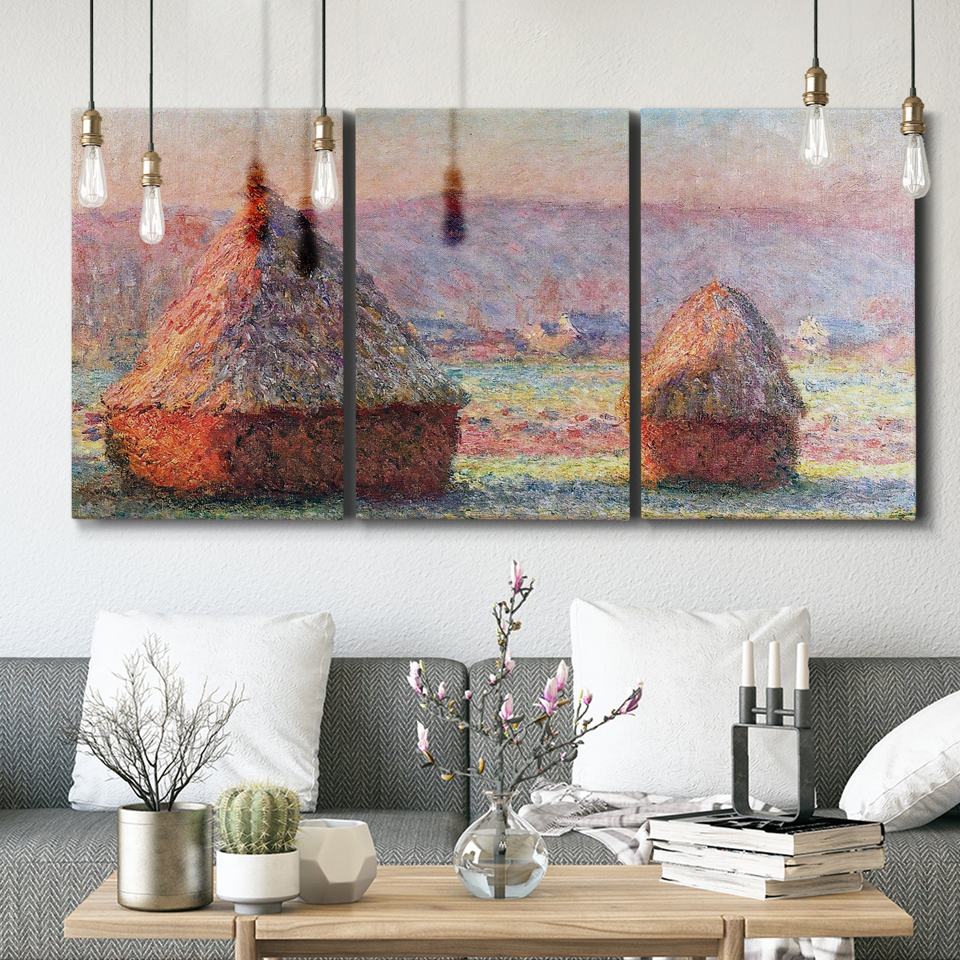 Three-panel canvas wall art featuring winter grainstacks glowing at sunset, displayed in a modern living room above seating.