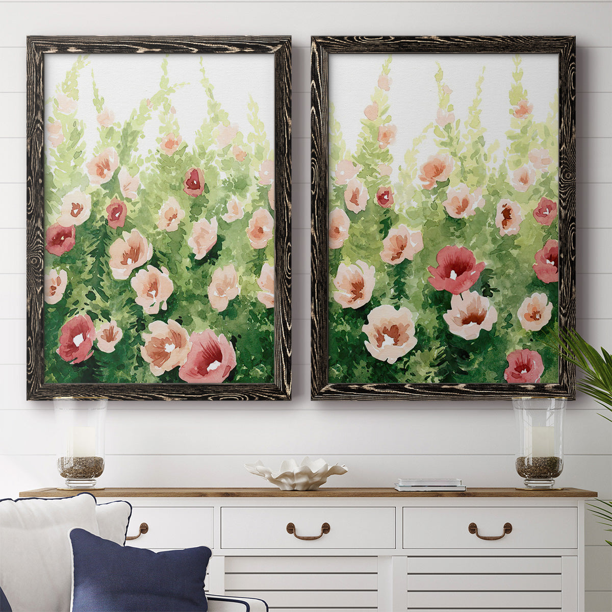 Set of two black barnwood framed canvas prints depicting a coordinated art pair of a field of pink coral and white flowers rendered as luminous impressionistic floral paintings above a dining room sideboard.