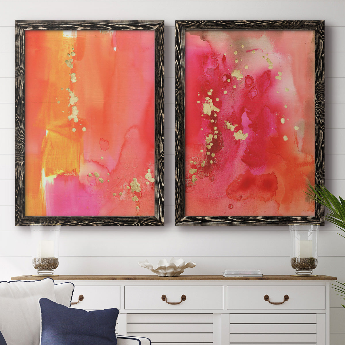 Set of two black barnwood framed canvas prints depicting a coordinated art pair of luminous coral orange and pink color fields with gold flecks rendered as glamorous fluid abstracts above a dining room sideboard.