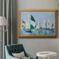 Coastal harbor watercolor painting in an ornate antique gold frame displayed in a neutral interior setting.